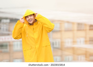 Young Asian Man In Raincoat On City Street