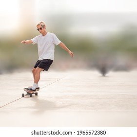 Young asian man riding skateboard on city street blurred background. Male in short pants practice surf skate board exercise on urban road. Trendy outdoor extreme sport in Thailand though dangerous.