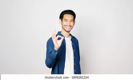 Young Asian Man Showing Ok Hand Sign And Smiling While Standing Over Isolated Grey Background, Happy Asia Male Showing Ok Hand, Positive People Gesture