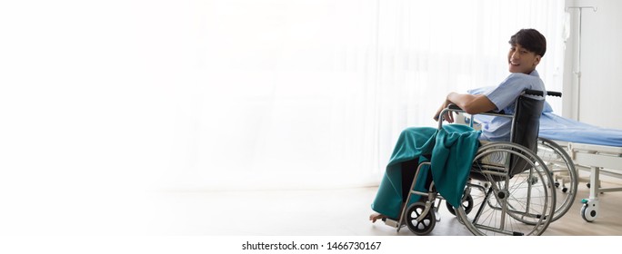 Young Asian Man Sitting On A Wheelchair In The Hospital With Smiley Face.