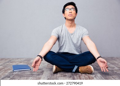 Young Asian Man Sitting On The Floor And Meditating 