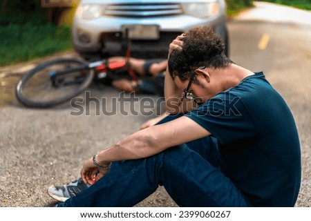 Young Asian man sitting on the road worrying after driving car crashes into a cyclist falls and injures, Cyclist in Need of Urgent Aid, Unexpected Roadside Encounter, Outdoor Mishaps Car Crash.
