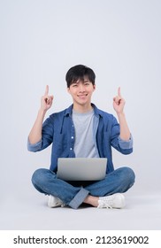 Young Asian Man Sitting And Using Laptop On White Background