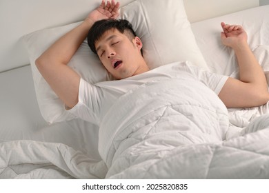 Young Asian Man Sleeping And Snoring Loudly Lying In The Bed
