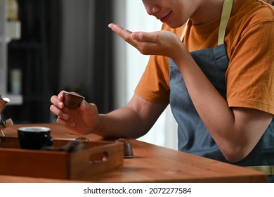 Young Asian Man Smelling Roasted Coffee Beans In His Hands.