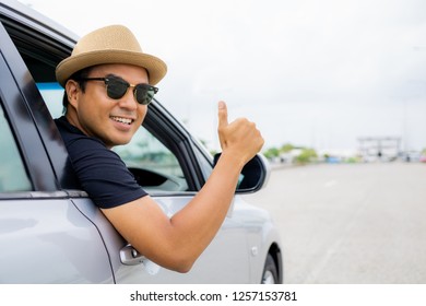 Young Asian Man Smiling And Showing Thumb Up In His Car.