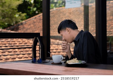 young Asian man sneezing while relaxing on the balcony of a cafe. - Powered by Shutterstock