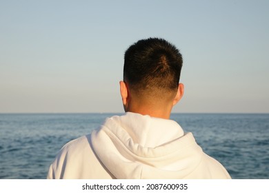 Young Asian Man Standing Against Nature Landscape In Deep Thought. Back View.