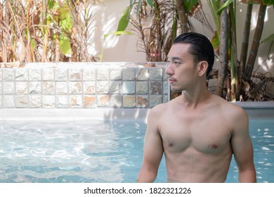 Young Asian Man Standing In Swiming Pool On Holiday.