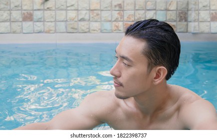 Young Asian Man Standing In Swiming Pool On Holiday.