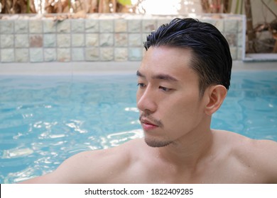 Young Asian Man Standing In Swiming Pool On Holiday.