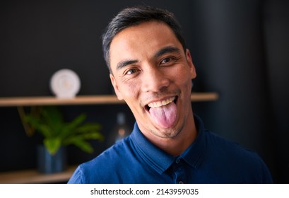 A Young Asian Man Sticks Out His Tongue In A Silly Pose At The Office