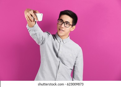 Young Asian Man Taking Selfie On Color Background