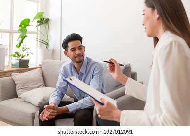 Young Asian man talking his problems with professional psychologist while conducting a consultation and making notes to seek advice and therapy