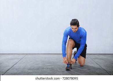 Young Asian Man Tie Sport Shoe Laces Before Running Outdoors