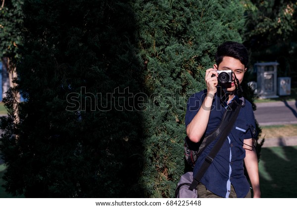 Young asian man  touching with camera\
before photographing.