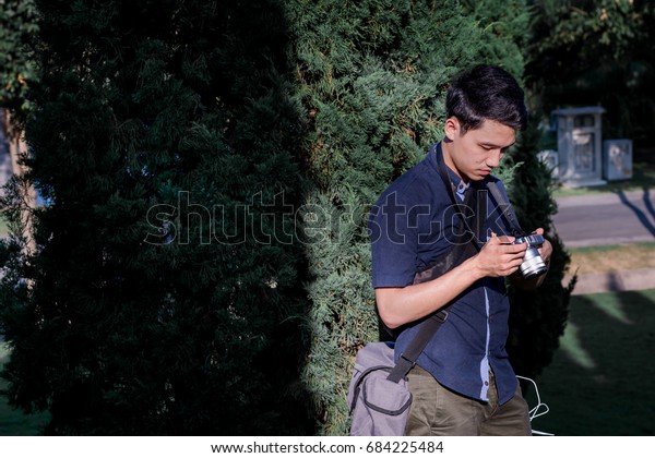 Young asian man  touching with camera\
before photographing.