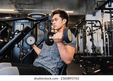 Young Asian man training with dumbbells - Powered by Shutterstock