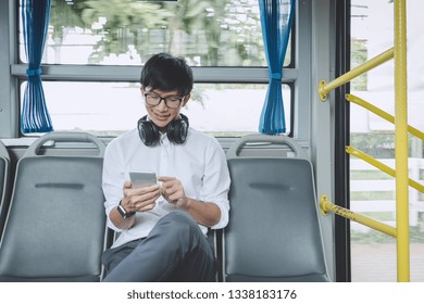 Young Asian man traveler sitting on a bus using smartphone watch video or listening music while smile of happy, transport, tourism and road trip concept. - Powered by Shutterstock