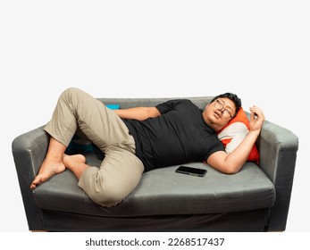 young asian man use eyeglasses and black t-shirt lay on the grey couch get sleep.asian lazy man with.boy enjoy the living room sofa and sleep mobile phone beside him white background fat guy sleeping - Powered by Shutterstock