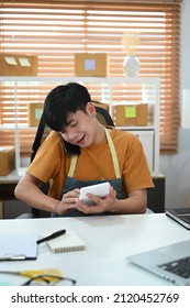 Young Asian Man Using Calculator And Confirming Orders From Customer On Mobile Phone.