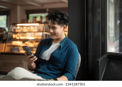 Young Asian man using smart phone in cafe - Powered by Shutterstock