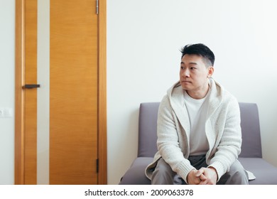 Young Asian Man Waiting For An Interview Or Meeting Sitting In The Hallway In The Waiting Room. Student Or Entrant In The Reception For Exam Or Employment . Male Patient In Office A Hospital Or Clinc