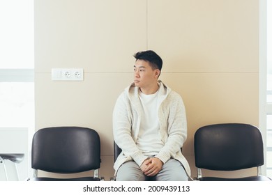 young asian man waiting for an interview or meeting sitting in the hallway in the waiting room. Student or entrant in the reception for exam or employment hr. Male patient in office a hospital clinic - Powered by Shutterstock