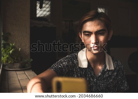 A young asian man waits for a reply from his girlfriend who has not replied in a long time. Possibly seenzoned. Depressing scene in a dim room.