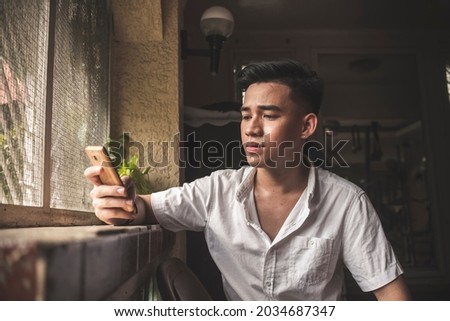 A young asian man waits for a reply from his girlfriend who has not replied in a long time. Possibly seenzoned. Depressing scene in a dim room.