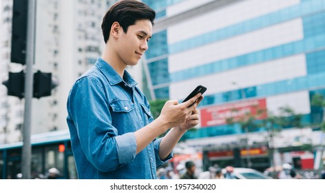Young Asian man walking and using smartphone on the street - Shutterstock ID 1957340020