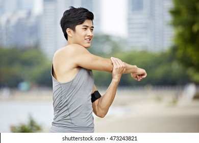 Young Asian Man Warming Up By Stretching Arms Before Exercise.