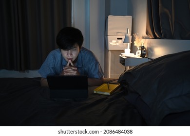 Young Asian Man Watching Movies On Digital Tablet At Night.