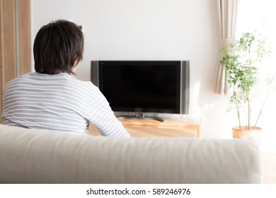 Young Asian Man Watching Tv In  The Living Room