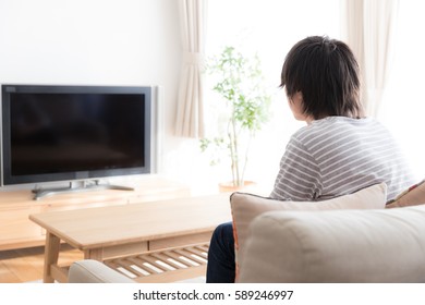 Young Asian Man Watching Tv In  The Living Room