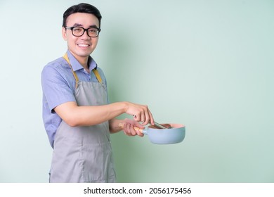 Young Asian man wearing apron posing on green background - Powered by Shutterstock