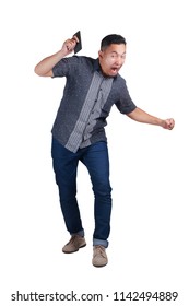 Young Asian Man Wearing Blue Jeans And Batik Shirt Angry For Having Bad News On Phone. Ready To Throw The Phone. Isolated On White. Full Body Portrait