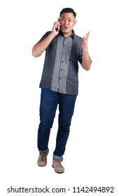 Young Asian Man Wearing Blue Jeans And Batik Shirt Talking At Phone, Cried And Worried Expression. Isolated On White. Full Body Portrait