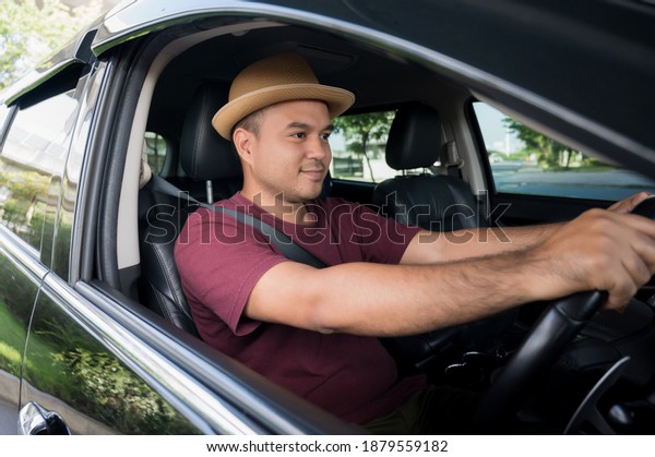 Young asian man\
wearing hat and driving\
car.