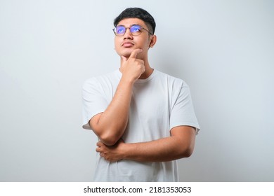 Young Asian Man Wearing Plain White Shirt Standing Over White Background Thinking Worried About A Question, Concerned And Nervous With Hand On Chin