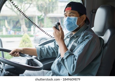 Young Asian Man Wearing Protective Mask During Driving. Professional Truck Driver Using Radio Communicate And Talk. Smile And Service With Friendship Of Truck Driver, Transportation And Delivery