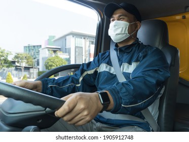 A Young Asian Man Wearing A Protective Mask Is Driving A Car With Confidence. Professional Truck Driver In Long Transportation. Delivery Man Transport Parcel Based On Customer Orders.