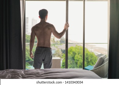 Young asian man wearing short pant opening the door to see outside view in the morning. - Powered by Shutterstock