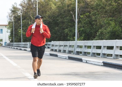 Young asian man wearing sportswear running outdoor. Portraits of Indian man jogging on the road. Training athlete outdoor concept.