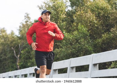 Young asian man wearing sportswear running outdoor. Portraits of Indian man jogging on the road. Training athlete outdoor concept. - Powered by Shutterstock