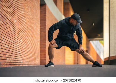 Young Asian Man Wearing Sportswear Running Outdoor. Portraits Of Indian Man Stretching Leg Before Running On The Road. Training Athlete Work Out At Outdoor Concept.