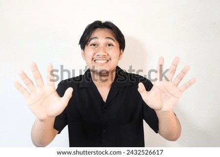 Young Asian man wearing t-shirt over isolated white background doing stop sign with palm.