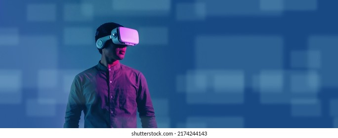 Young Asian Man Wearing VR Headset For Entertainment In The Metaverse. Augmented Reality. Future Digital Technology Game And Entertainment. Metaverse Technology Concept.