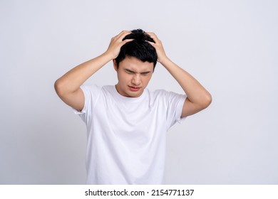 Young Asian man wearing white t-shirt touching head temples experiencing stress having troubles difficulties to resolve issues, He has a headache and panic on a studio white background.