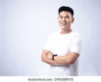 A young Asian man, wearing a white shirt and black watch, smiles confidently with his arms crossed. The background is plain white, highlighting the subject's professional and approachable demeanor - Powered by Shutterstock